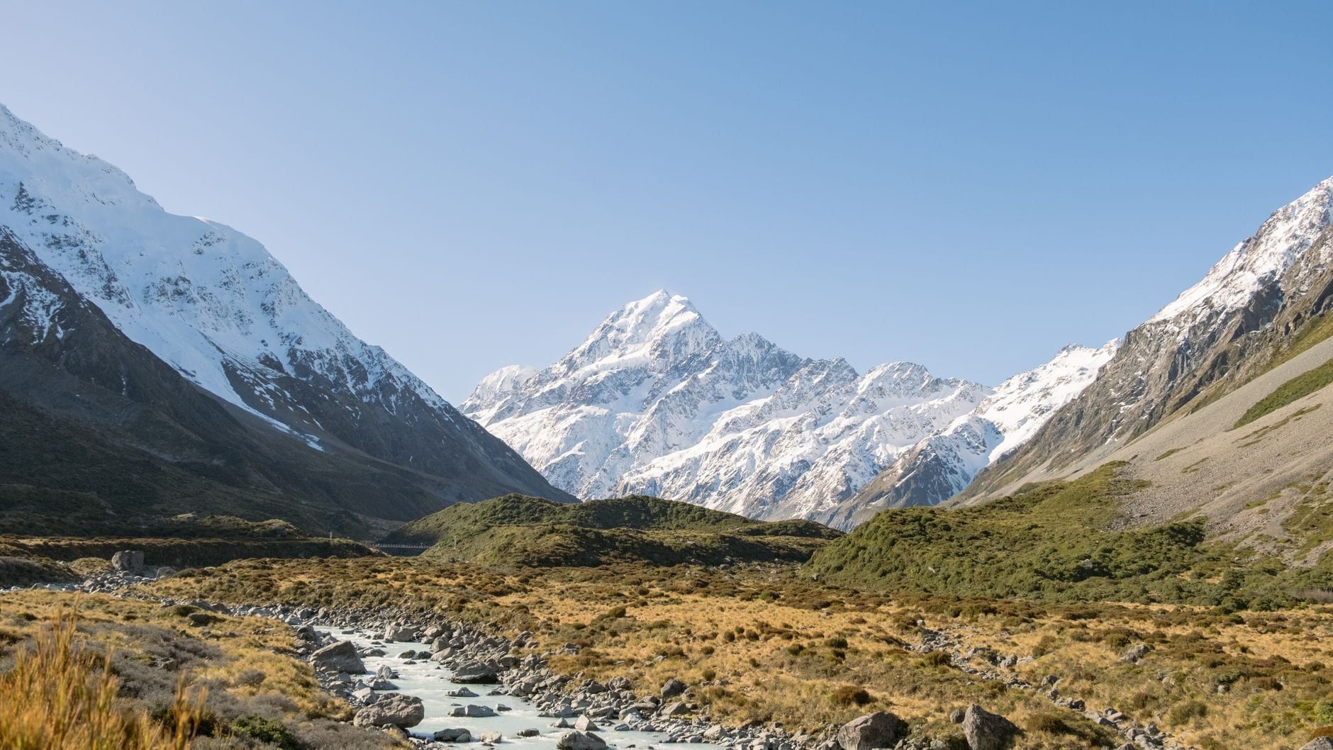 Snow-capped Mount Cook rises at the head of Hooker Valley above a braided riverbed in Aoraki Mount Cook National Park.