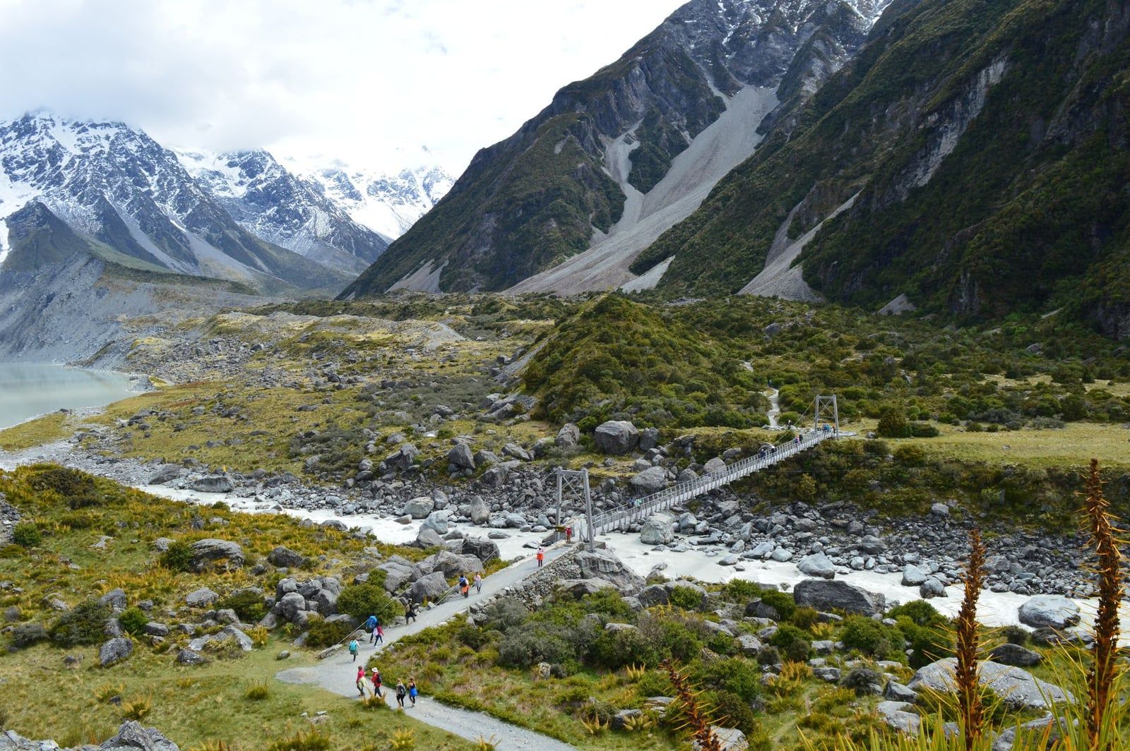 Hikers cross a suspension bridge spanning the Hooker River on the Hooker Valley Track in Aoraki Mount Cook National Park.
